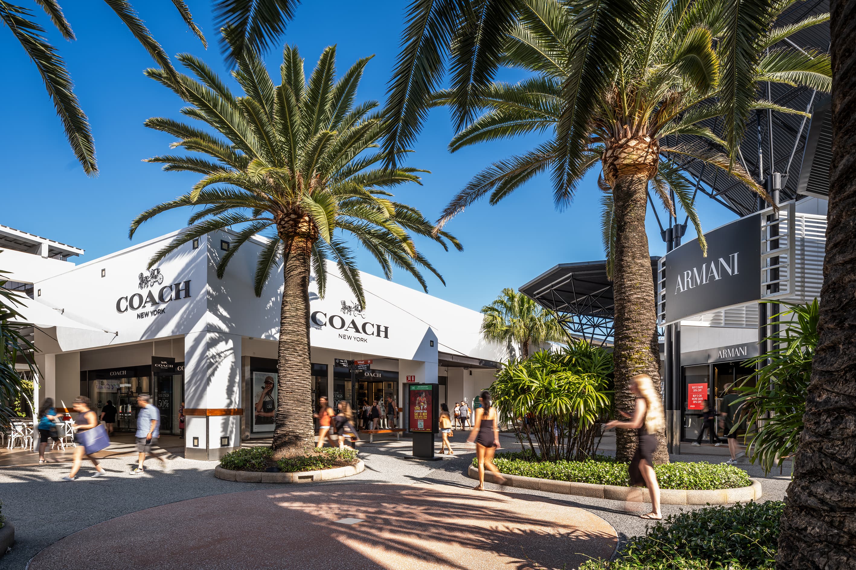 Outdoor retail precinct with Coach and Armani stores set behind palm tree